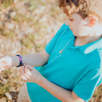 Young person seen from overhead wearing a God Bless America for Kids and Teens woven bracelet with an American flag