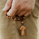 close up of hand holding HOLY LAND olive wood bead and cross PEACE Prayer Chaplet