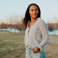 Woman in park in jeans and a striped shirt looking over her shoulder wearing Benedictine Blessing Bracelets