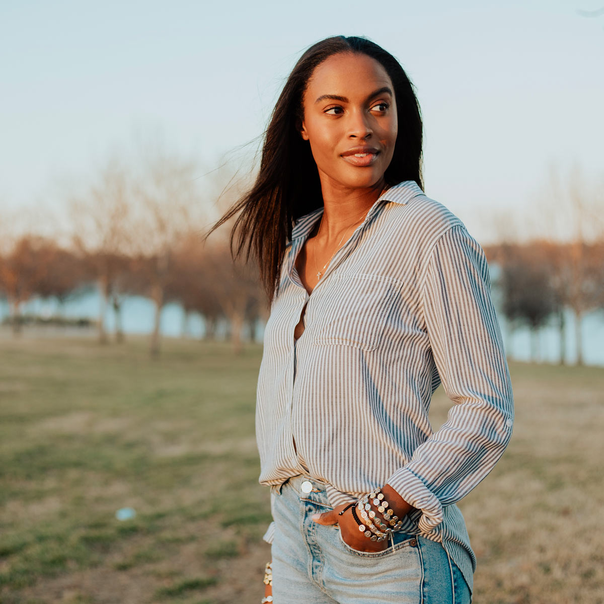 Woman in park in jeans and a striped shirt looking over her shoulder wearing Benedictine Blessing Bracelets