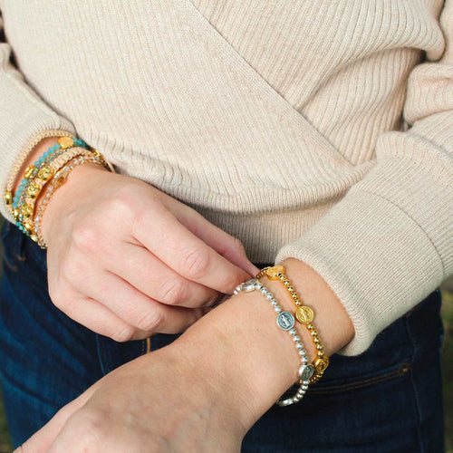 close up of woman wearing silver and gold Benedictine Birthday Blessing Bracelets
