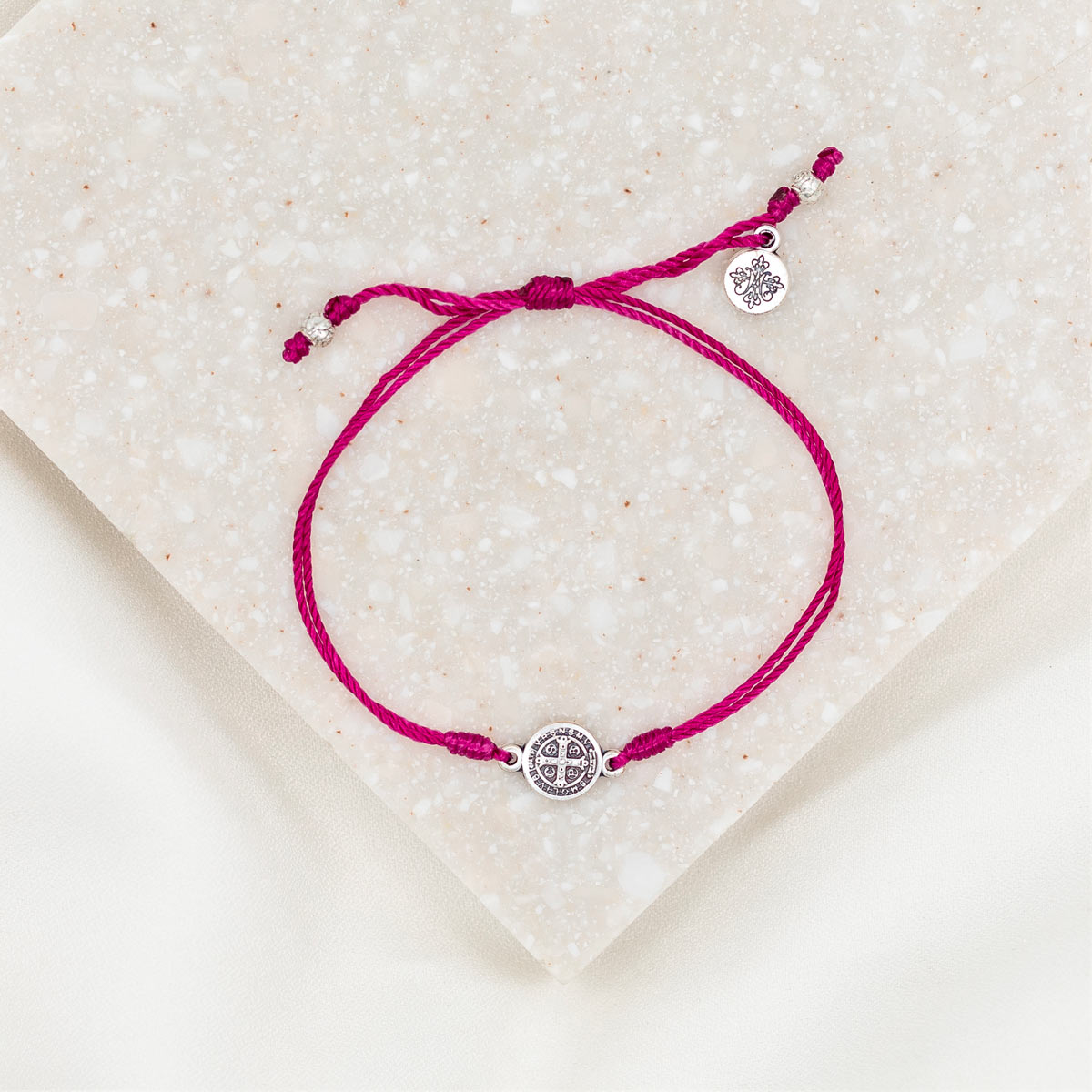 silver-tone St. Benedict medal on maroon bracelet cording with a slipknot closure