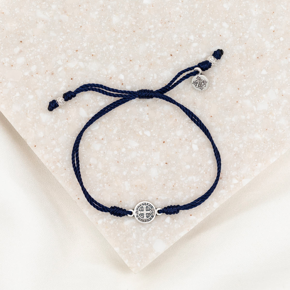 silver-tone St. Benedict medal on navy bracelet cording with a slipknot closure