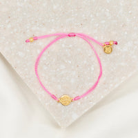 gold-tone St. Benedict medal on pink bracelet cording with a slipknot closure