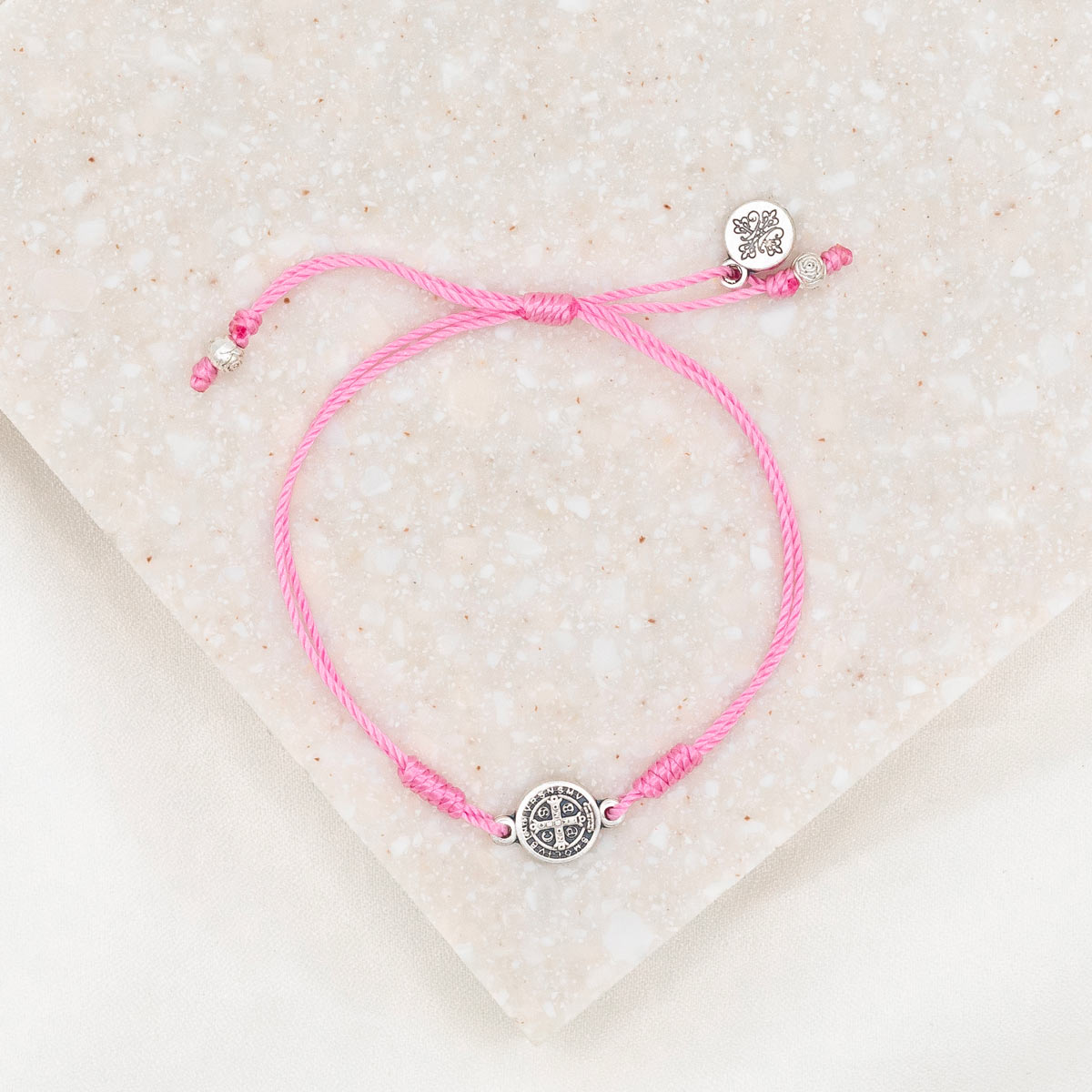 silver tone St. Benedict medal on pink bracelet cording with a slipknot closure