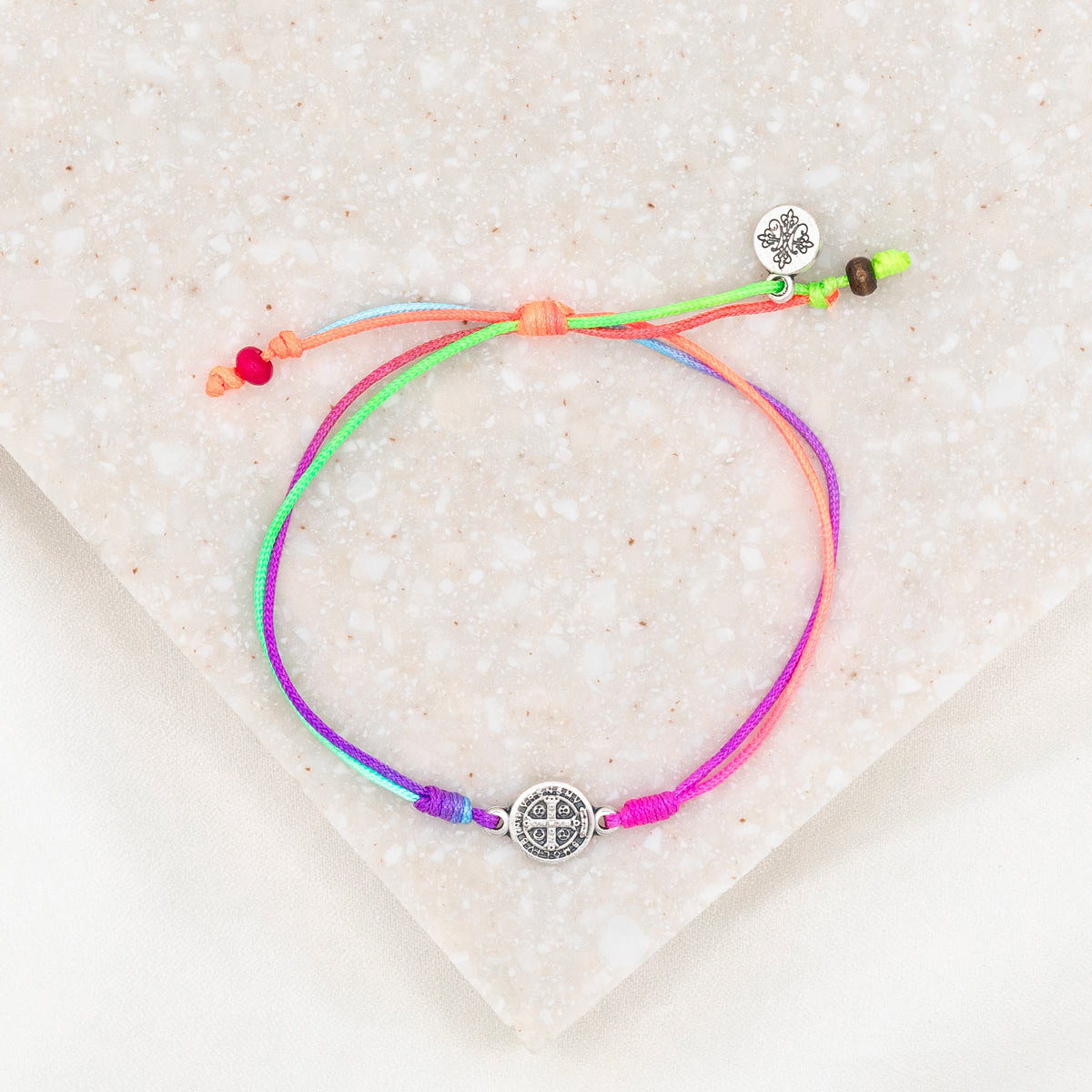silver-tone St. Benedict medal on rainbow colored bracelet cording with a slipknot closure