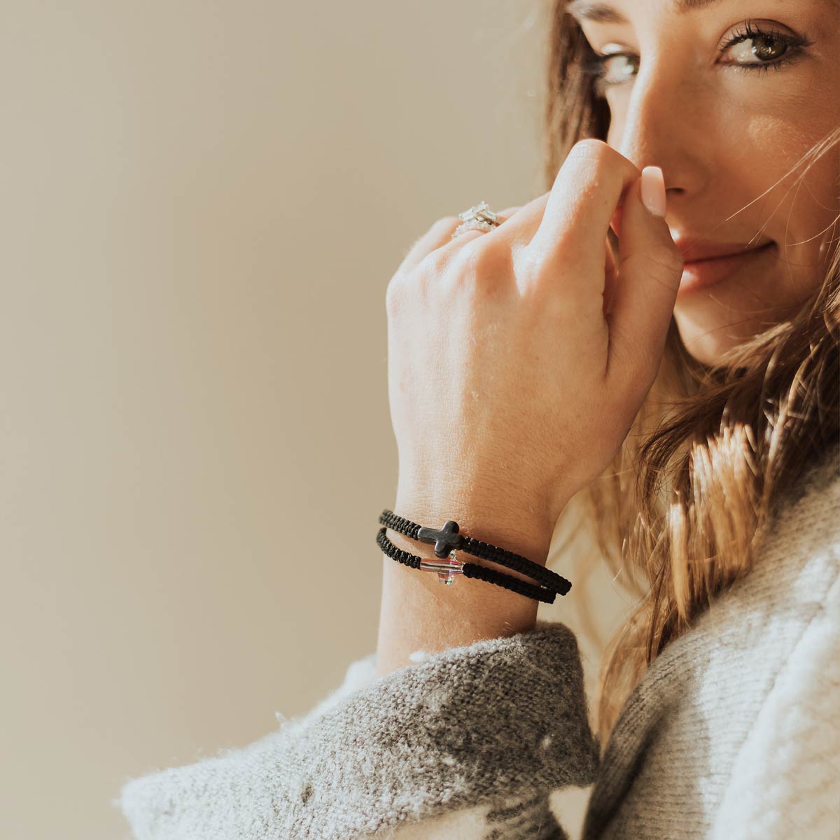 Faith Confirmed Crystal Cross Bracelet worn with a black howlite cross woven Faith Confirmed Bracelet