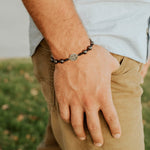 close up of man's wrist wearing black hemitite beaded handwoven benedictine blessing bracelet