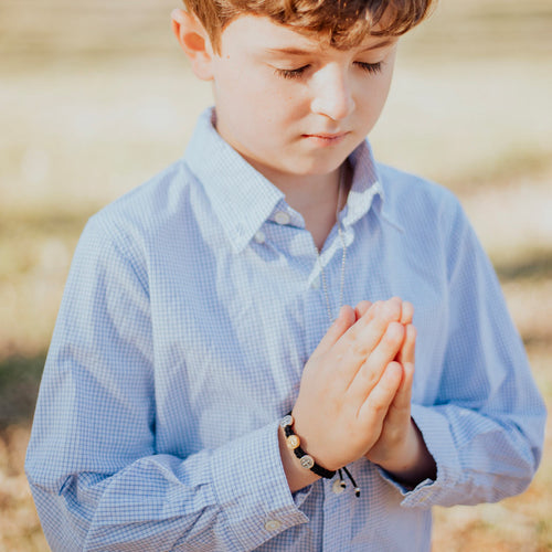 Child praying wearing First Holy Communion Child of God Bracelet