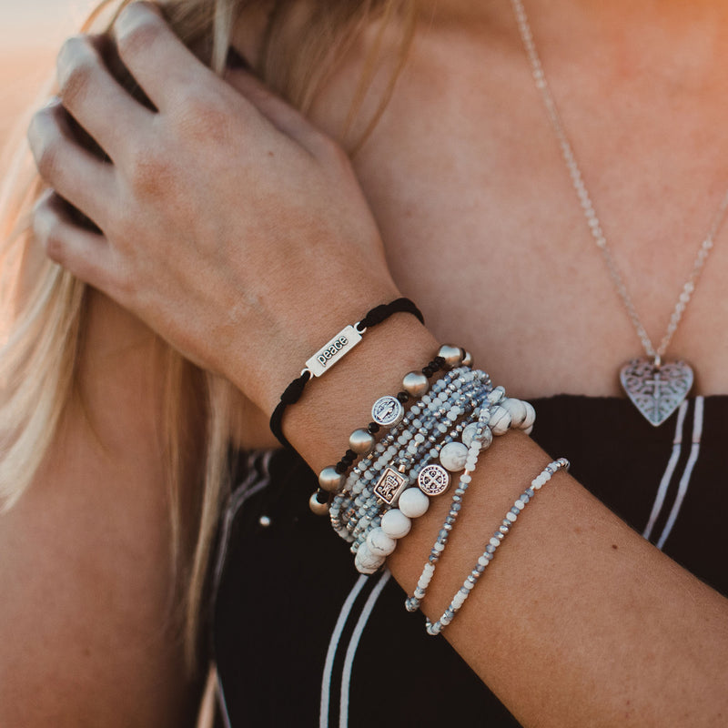 Woman wearing stack of Blessing Bracelets featuring the Peace White Howlite Power Blessing Bracelet