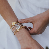 women's wrist with stack of Benedictine Medal bracelets with silver and gold tone beads