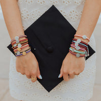 Woman wearing a stack of all the colors of School Spirit handwoven blessing bracelets.