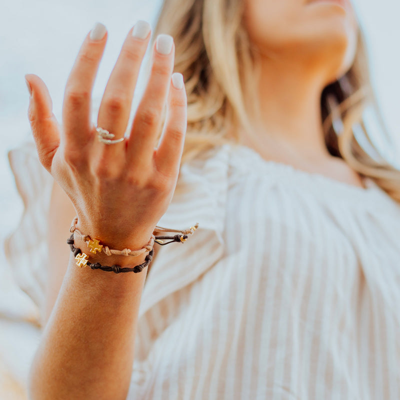 woman with her hand up in praise wearing Surrender Prayer Bracelets in brown and tan cording