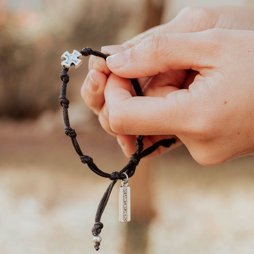Hands using the Surrender Prayer Bracelet knots as a chaplet for prayer